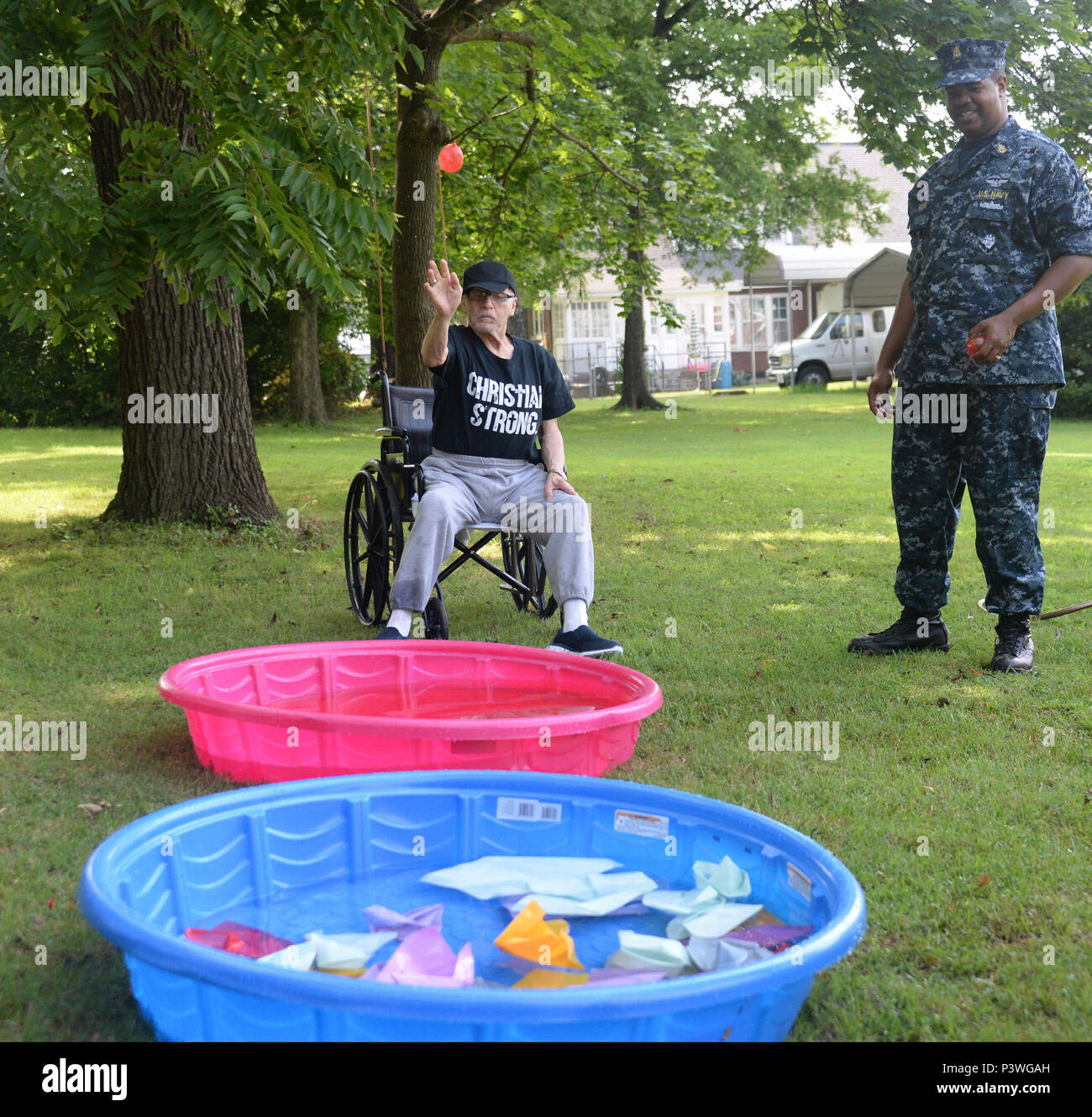 160722-N-FU443-017 NASHVILLE (July 22, 2016) Chief Aviation Boatswain’s Mate (Handling) Mario Johnson assists during an outdoor game where residents attempted to sink paper battleships with squirt guns and water balloons at the Azalea Trace Assisted Living facility. Several members of Navy Recruiting District Nashville volunteered for the event in order to reach out to local members of the community. (U.S. Navy photo by Mass Communication Specialist 1st Class Timothy Walter/Released) Stock Photo