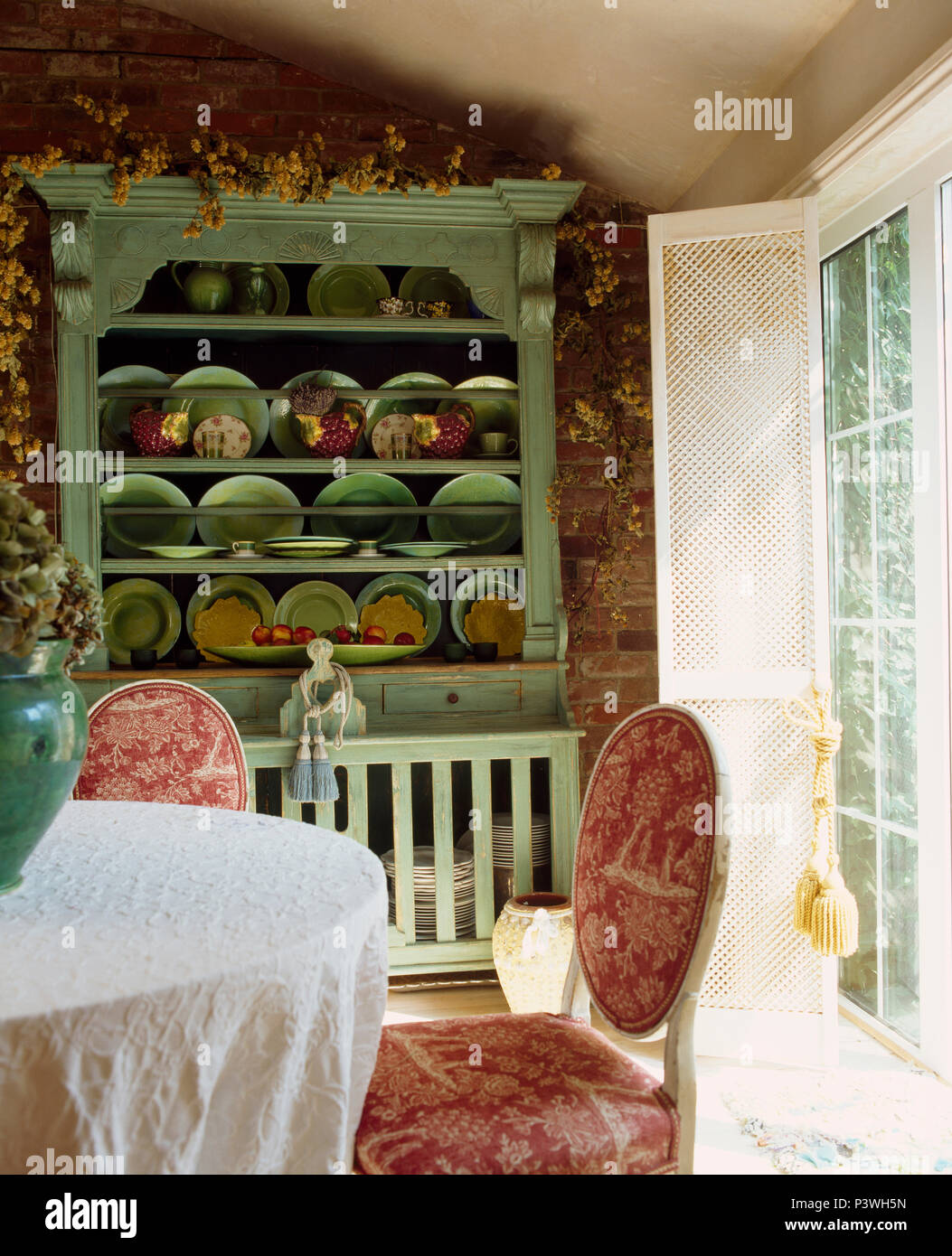 Pale green painted dresser with collection of rustic pottery in