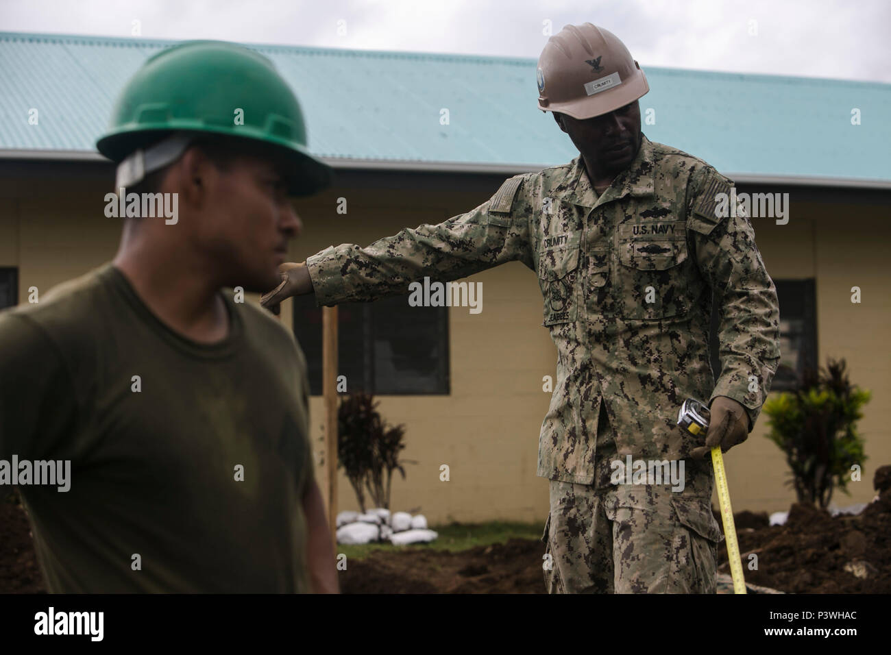 CAWACI, OVALAU, Fiji — Petty Officer Second Class Ray F. Crumity (Right) and Lance Cpl. J Guadelupe Venegas take a break from digging during vertical construction training, July 8, 2016, on Ovalau, Fiji. Marines and Sailors with Task Force Koa Moana conduct vertical construction training and infantry training on the island with members of the Republic of Fiji Military Force to increase interoperability and relations. Crumity, from Moreno Valley, California, is a steel worker with the task force, originally assigned to Company E, Naval Mobile Construction Battalion 4. Venegas, from San Gabriel, Stock Photo