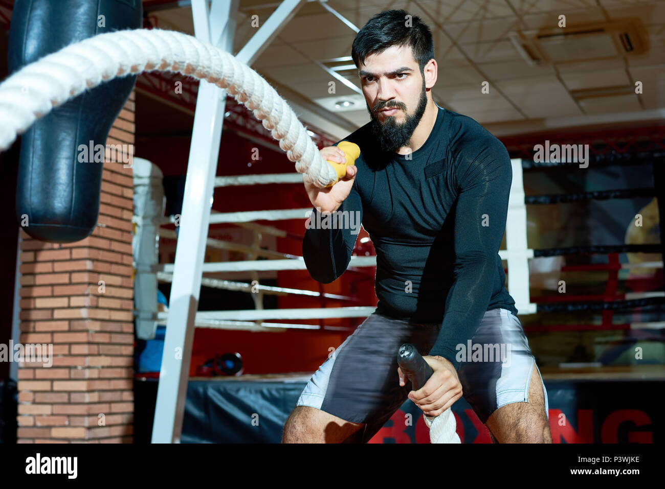 Brutal sportsman wriggling ropes in gym Stock Photo