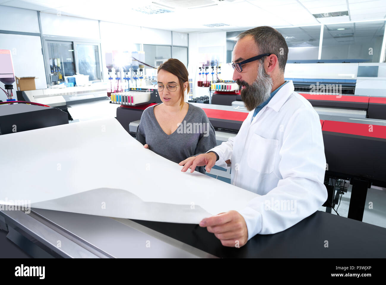 Printing team at industry plotter printer man and woman Stock Photo