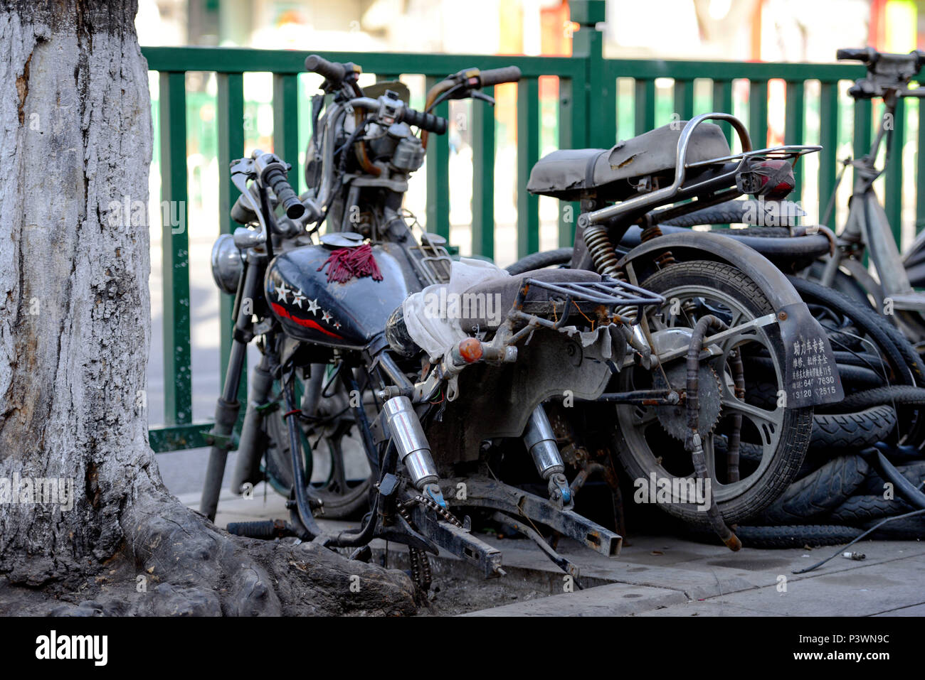 BEIJING, CHINA - MARCH 10, 2016: Bicycles, scooters and cars in Beijing streets.  The street side of the abandoned broken motorbikes. Stock Photo