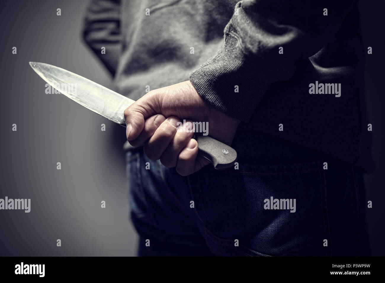 Criminal with knife weapon hidden behind his back Stock Photo