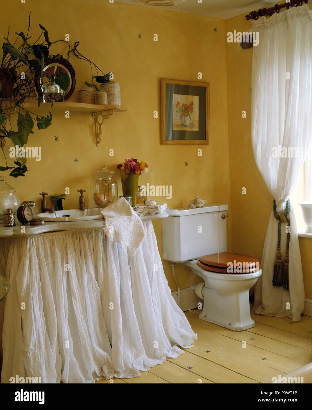 White muslin drapes belo basin in yellow bathroom with white voile
