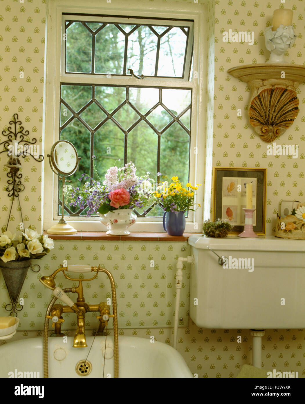 Leaded window above bath with brass taps and showerhead in cottage