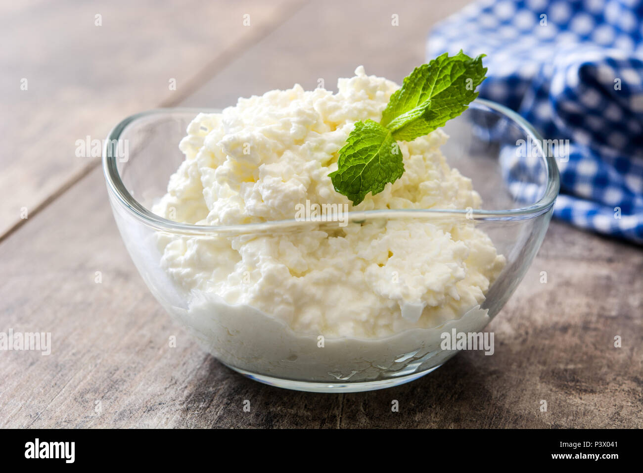 Fresh cottage cheese in a crystal bowl on wooden table. Stock Photo