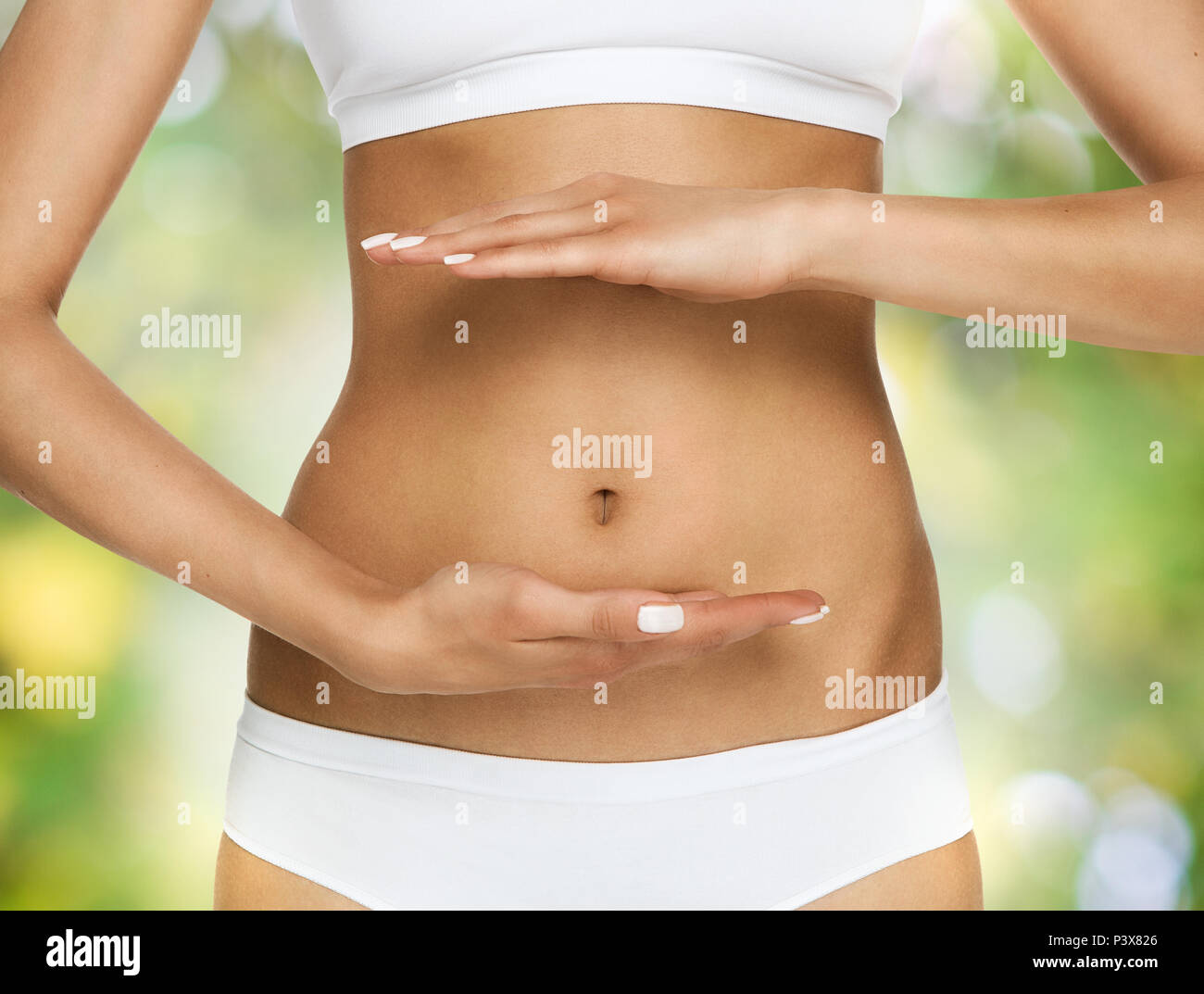 Pregnancy or diet concept, female hands protecting the stomach over nature background Stock Photo