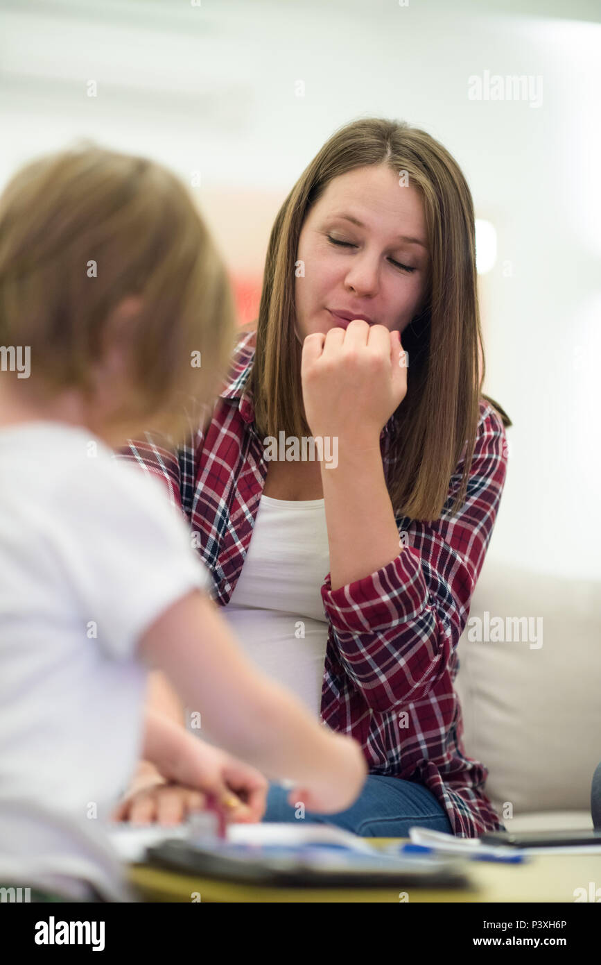 little cute daughter painting nails to her pregnant mom while relaxing
