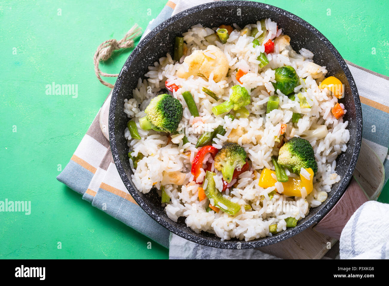 Vegetable risotto in skillet on green table. Rice with broccoli