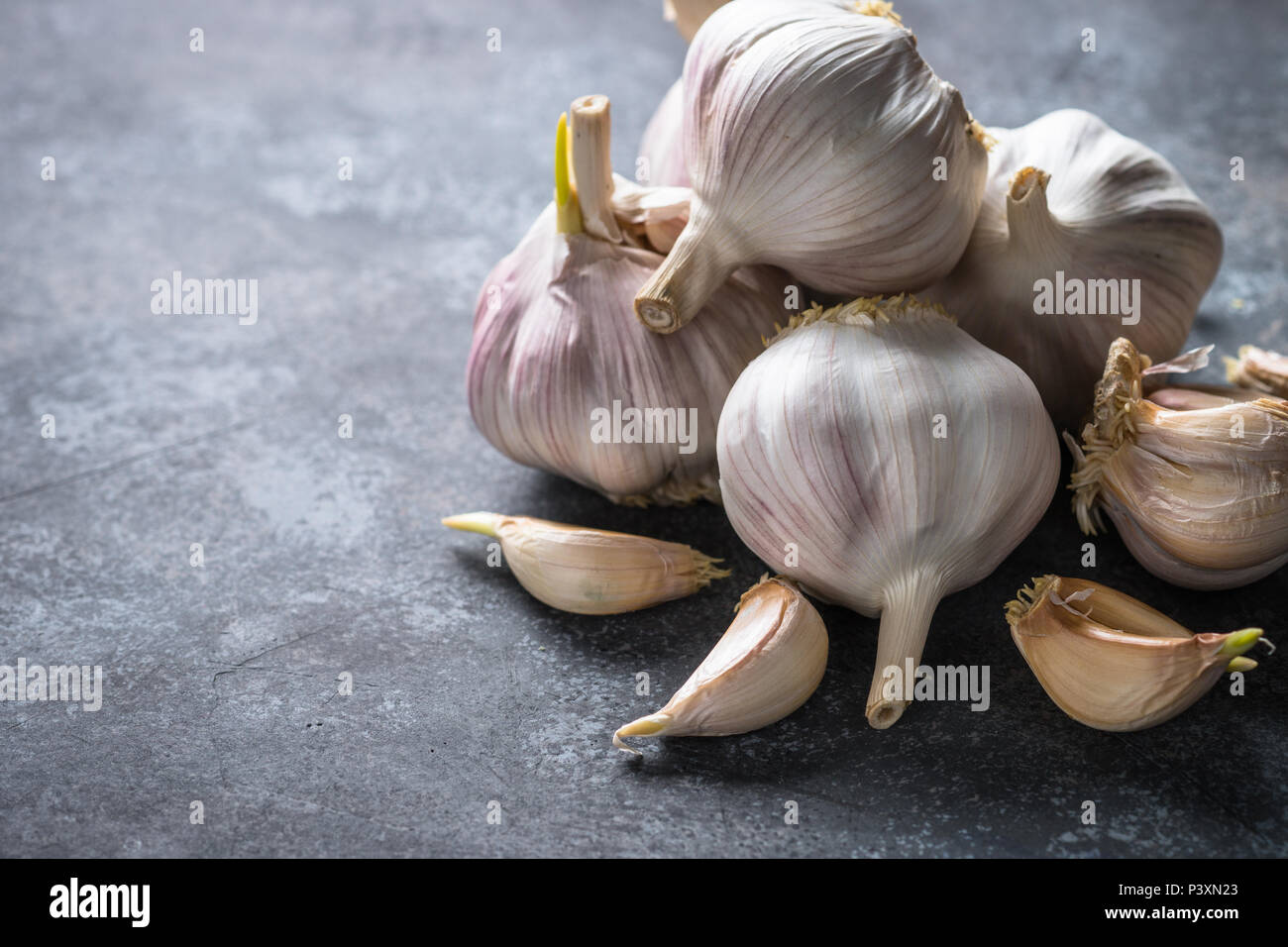 Garlic cloves on a dark stone background Stock Photo - Alamy