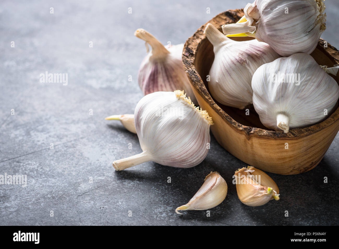 Garlic cloves on a dark stone background. Stock Photo