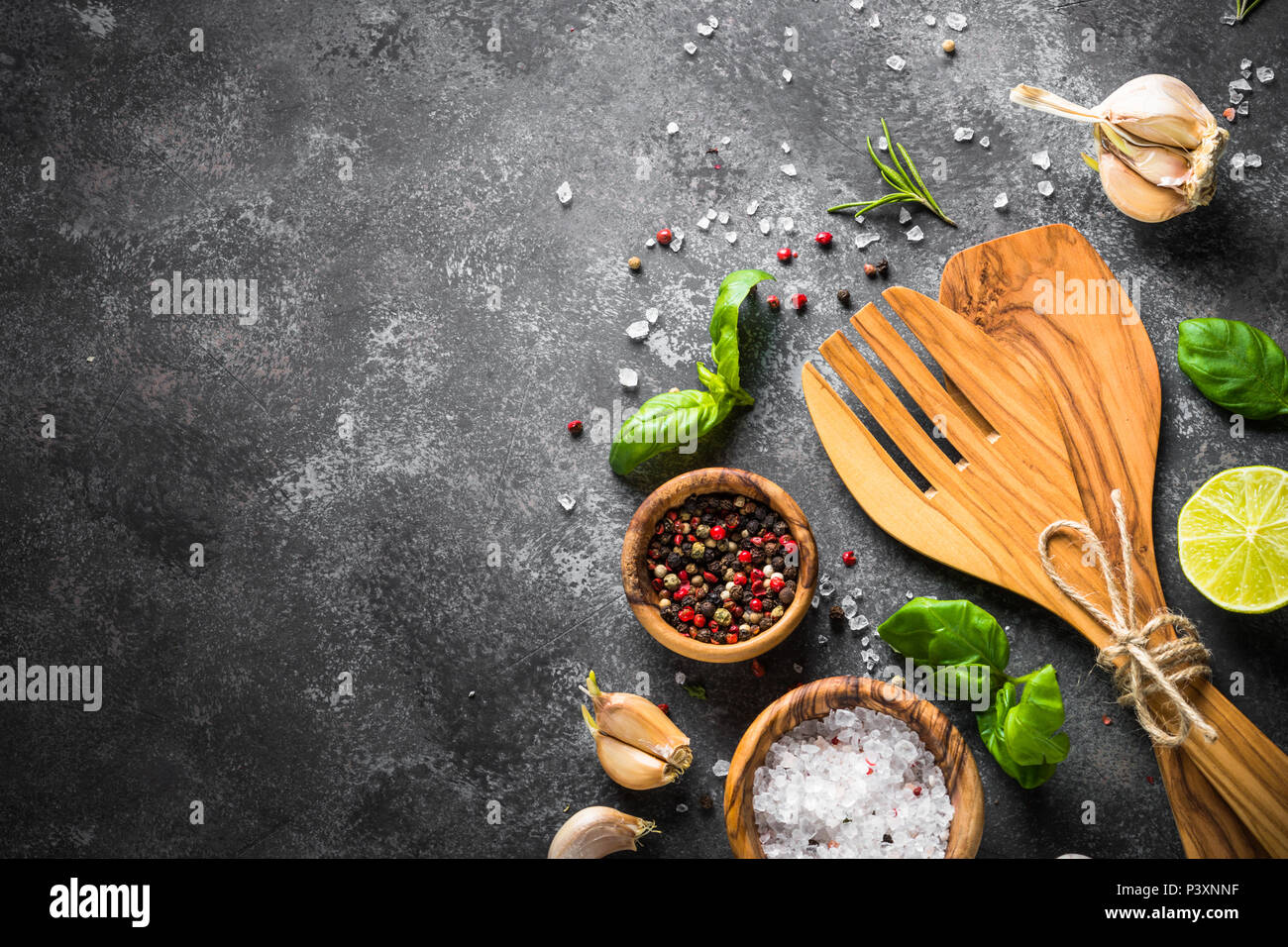 Food background. Herbs, spices and kitchen utensils on a black stone