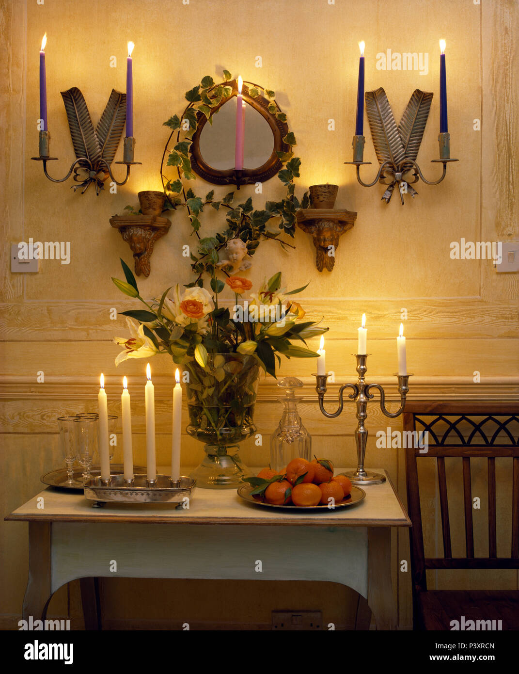 Lighted candles in wall lights on either side of mirror above painted
