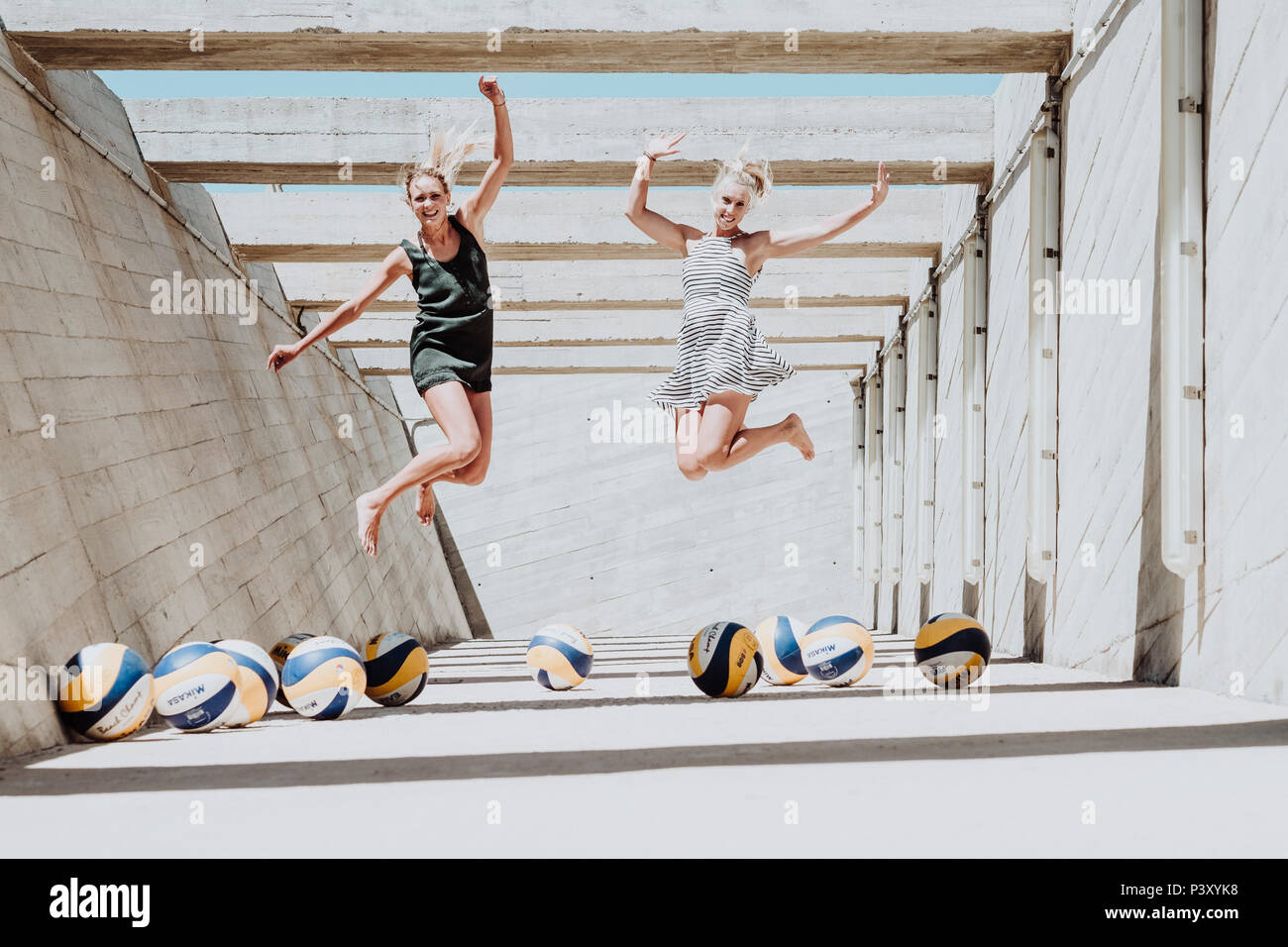 Beach Volley players, Karla Borger and Maggie Kozuch, jump for a portrait surrounded by volleyball balls Stock Photo