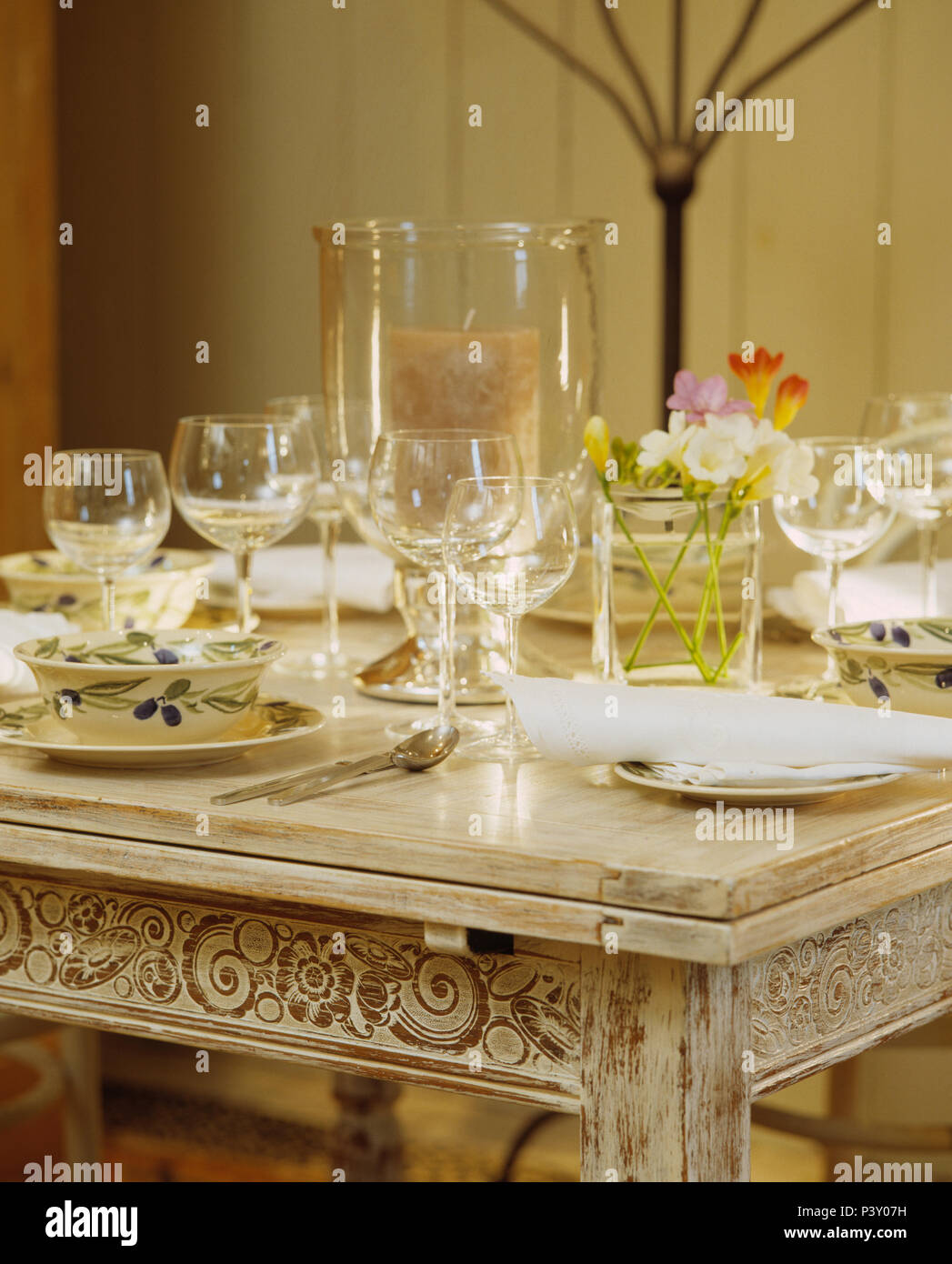Closeup of glassware and crockery on limewashed table set for lunch