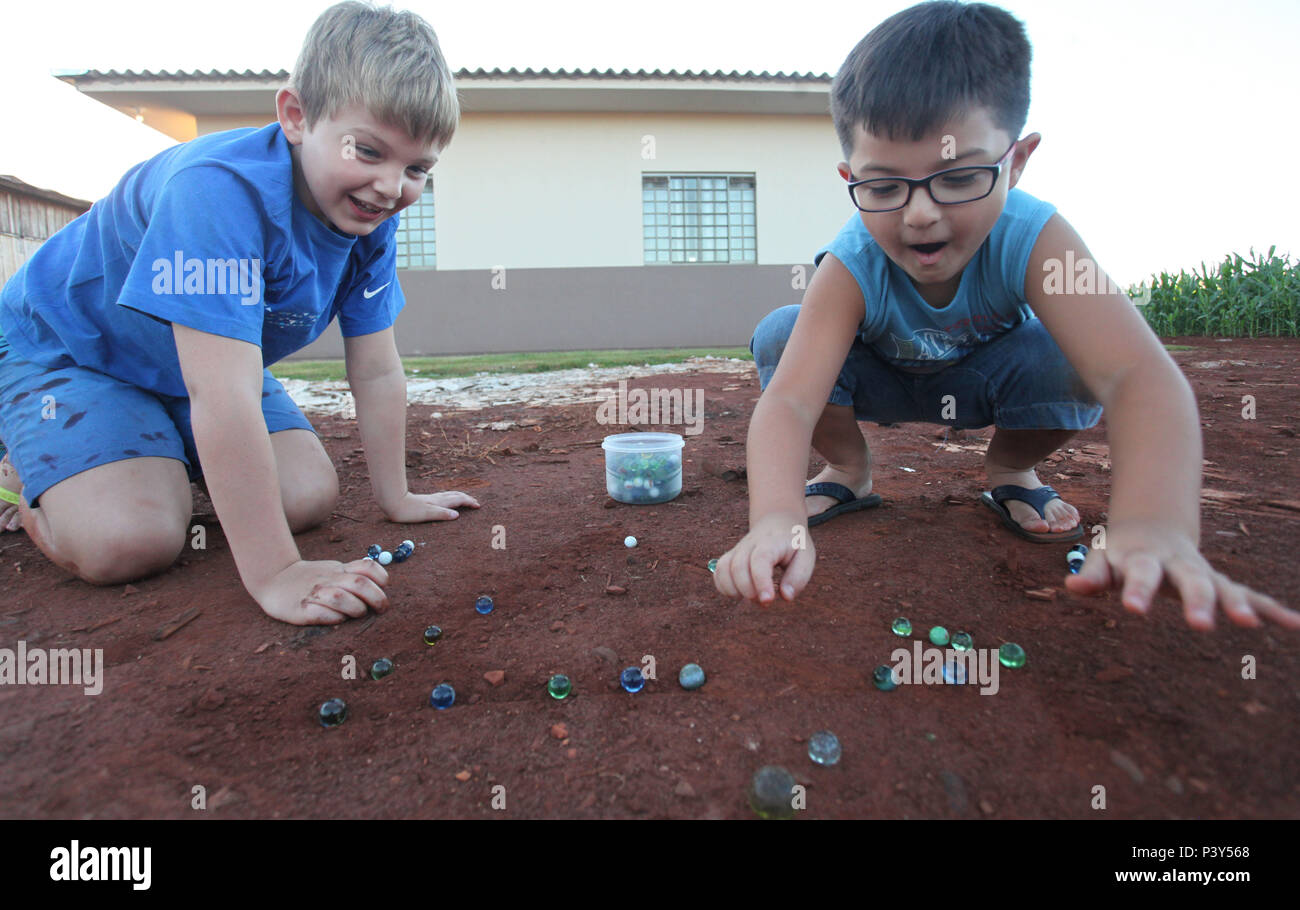 Apesar de toda a tecnologia disponível e de fácil acesso em Campo Mourão, na Região Centro-Oeste do Paraná, o jogo de bolinha de gude ainda fascina crianças do interior. Na foto, os estudantes Guilherme e Vitor disputam uma partida de bolinha de gude em um triângulo desenhado na terra, na casa dos avós de Guilherme. Stock Photo