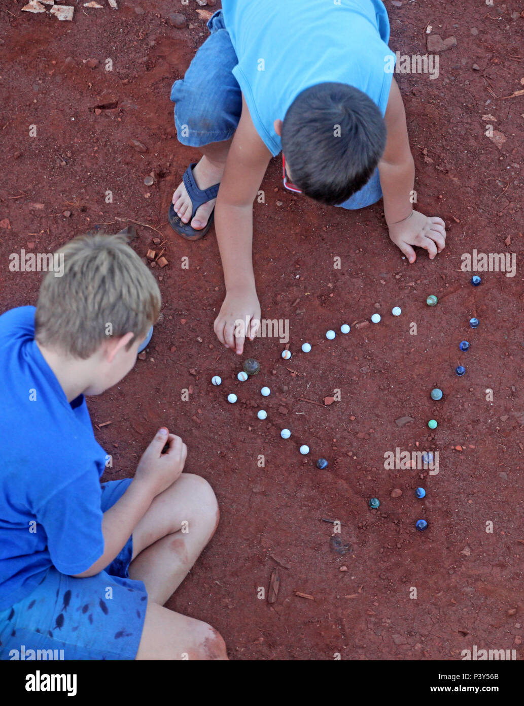 Apesar de toda a tecnologia disponível e de fácil acesso em Campo Mourão, na Região Centro-Oeste do Paraná, o jogo de bolinha de gude ainda fascina crianças do interior. Na foto, os estudantes Guilherme e Vitor disputam uma partida de bolinha de gude em um triângulo desenhado na terra, na casa dos avós de Guilherme. Stock Photo