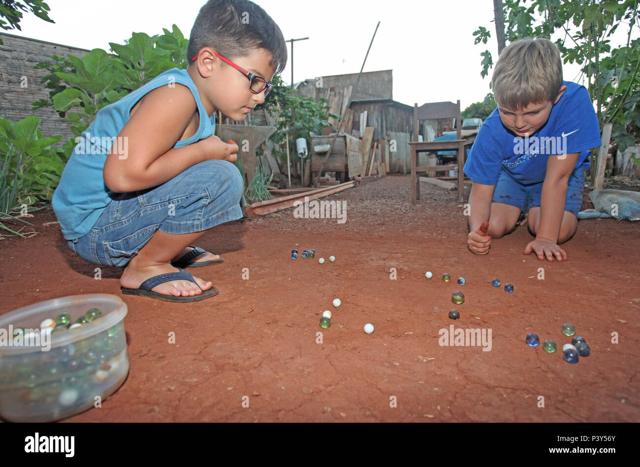 Apesar de toda a tecnologia disponível e de fácil acesso em Campo Mourão, na Região Centro-Oeste do Paraná, o jogo de bolinha de gude ainda fascina crianças do interior. Na foto, os estudantes Guilherme e Vitor disputam uma partida de bolinha de gude em um triângulo desenhado na terra, na casa dos avós de Guilherme. Stock Photo