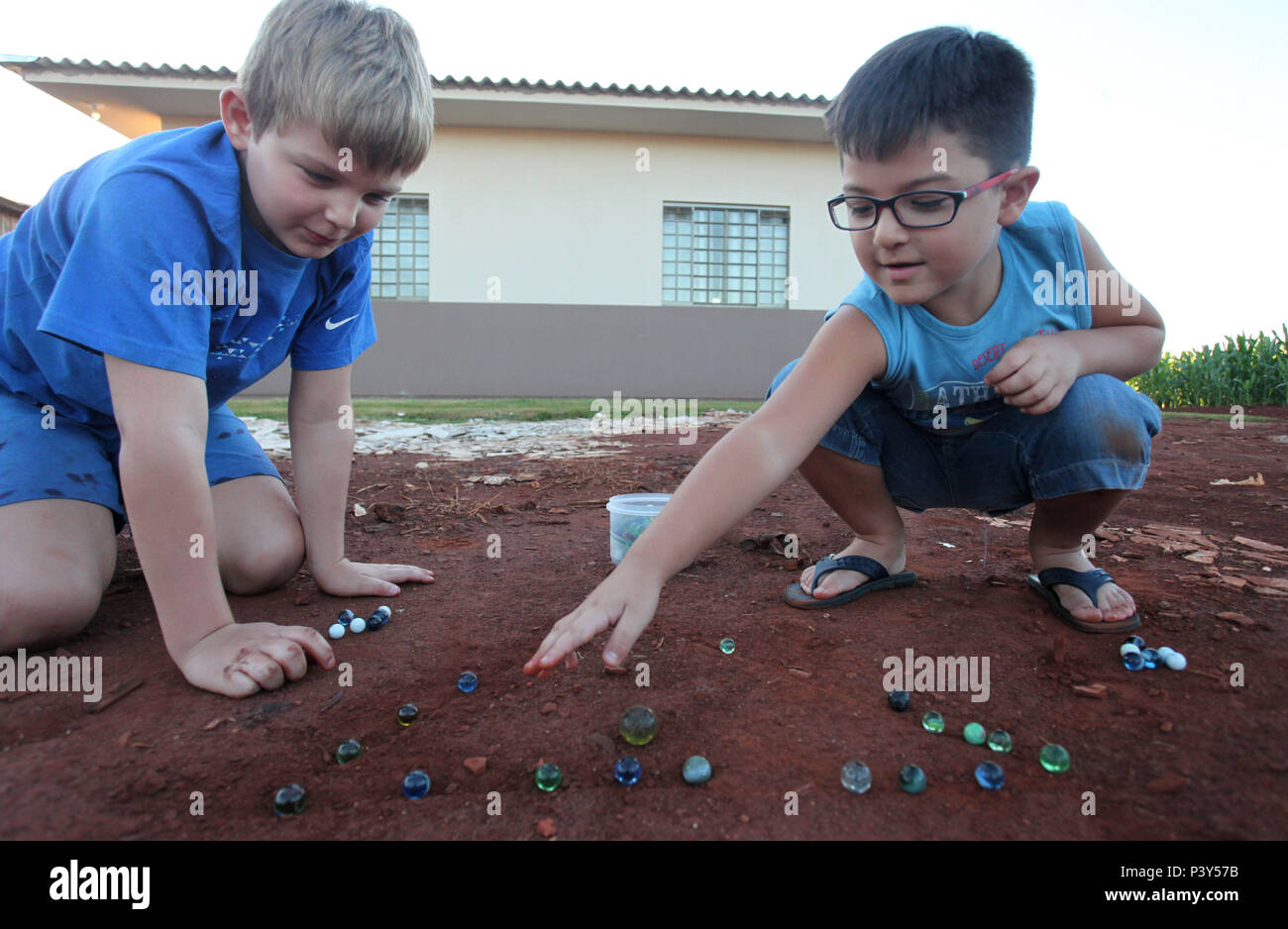 Apesar de toda a tecnologia disponível e de fácil acesso em Campo Mourão, na Região Centro-Oeste do Paraná, o jogo de bolinha de gude ainda fascina crianças do interior. Na foto, os estudantes Guilherme e Vitor disputam uma partida de bolinha de gude em um triângulo desenhado na terra, na casa dos avós de Guilherme. Stock Photo