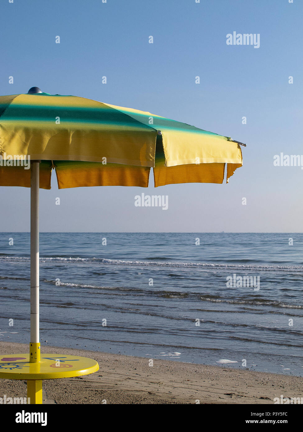 Beach umbrella yellow and green, with the background of the sea and blue sky Stock Photo