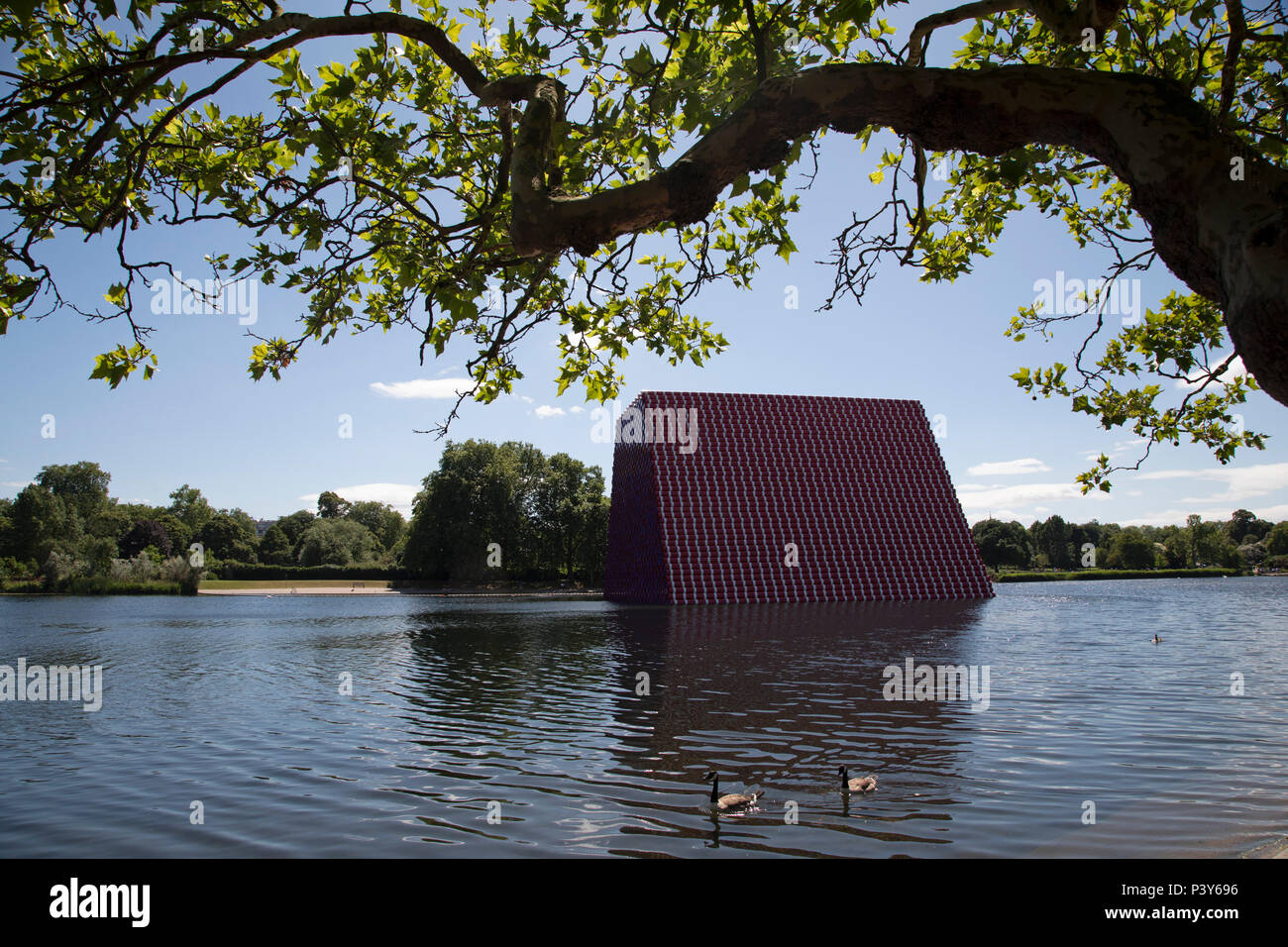 Art installation The Mastaba, by artist Christo, installed on the Serpentine lake in Hyde Park on June 18th 2018 in London, United Kingdom. The sculpture consists of 7,506 stacked barrels, painted in shades of red, white, blue and mauve. The completed piece forms part of an exhibition by Christo and his late wife, Jeanne-Claudes work, entitled Christo and Jeanne-Claude: Barrels and The Mastaba 19582018 to be held at The Serpentine Gallery. Stock Photo
