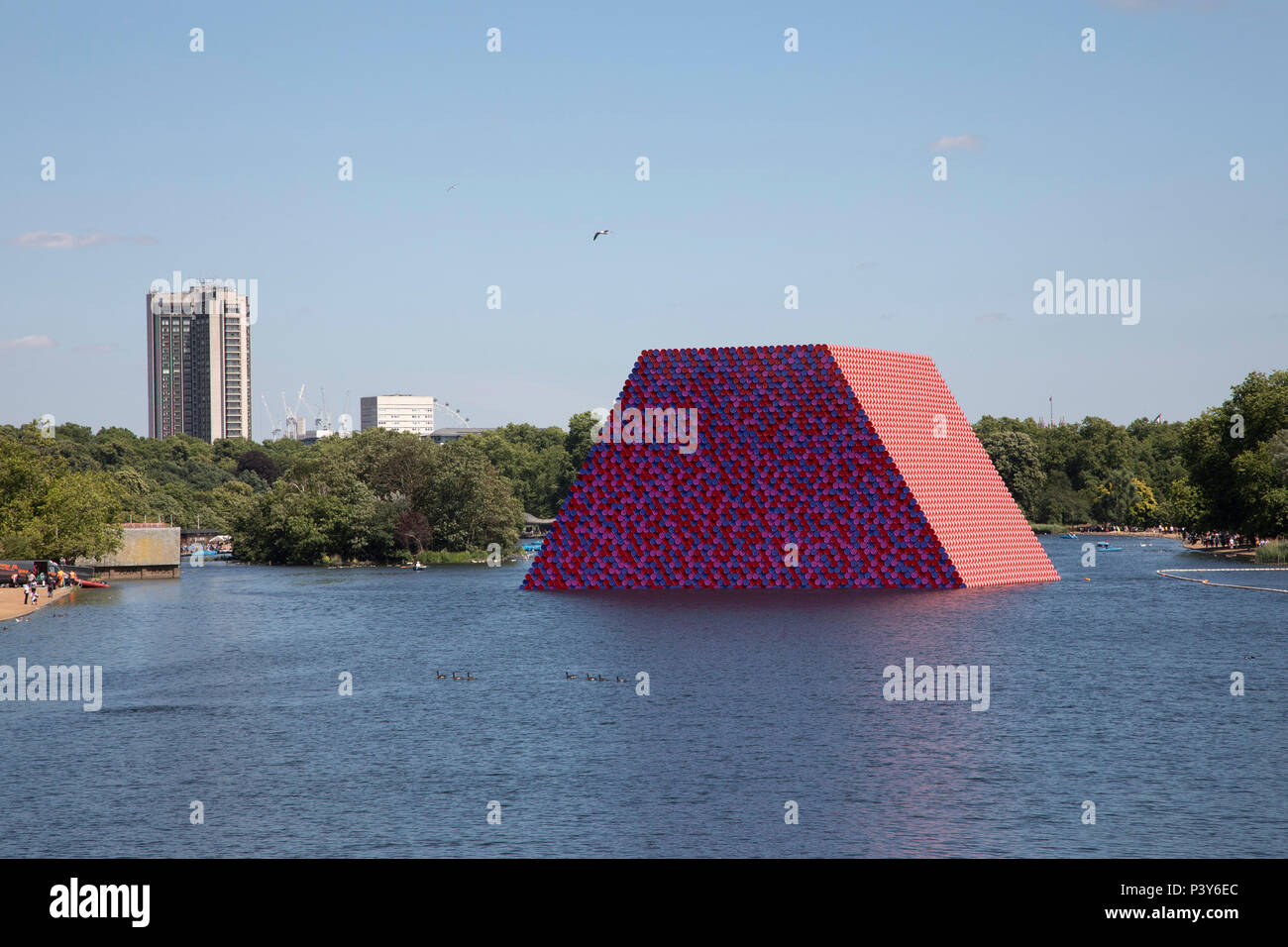Art installation The Mastaba, by artist Christo, installed on the Serpentine lake in Hyde Park on June 18th 2018 in London, United Kingdom. The sculpture consists of 7,506 stacked barrels, painted in shades of red, white, blue and mauve. The completed piece forms part of an exhibition by Christo and his late wife, Jeanne-Claudes work, entitled Christo and Jeanne-Claude: Barrels and The Mastaba 19582018 to be held at The Serpentine Gallery. Stock Photo