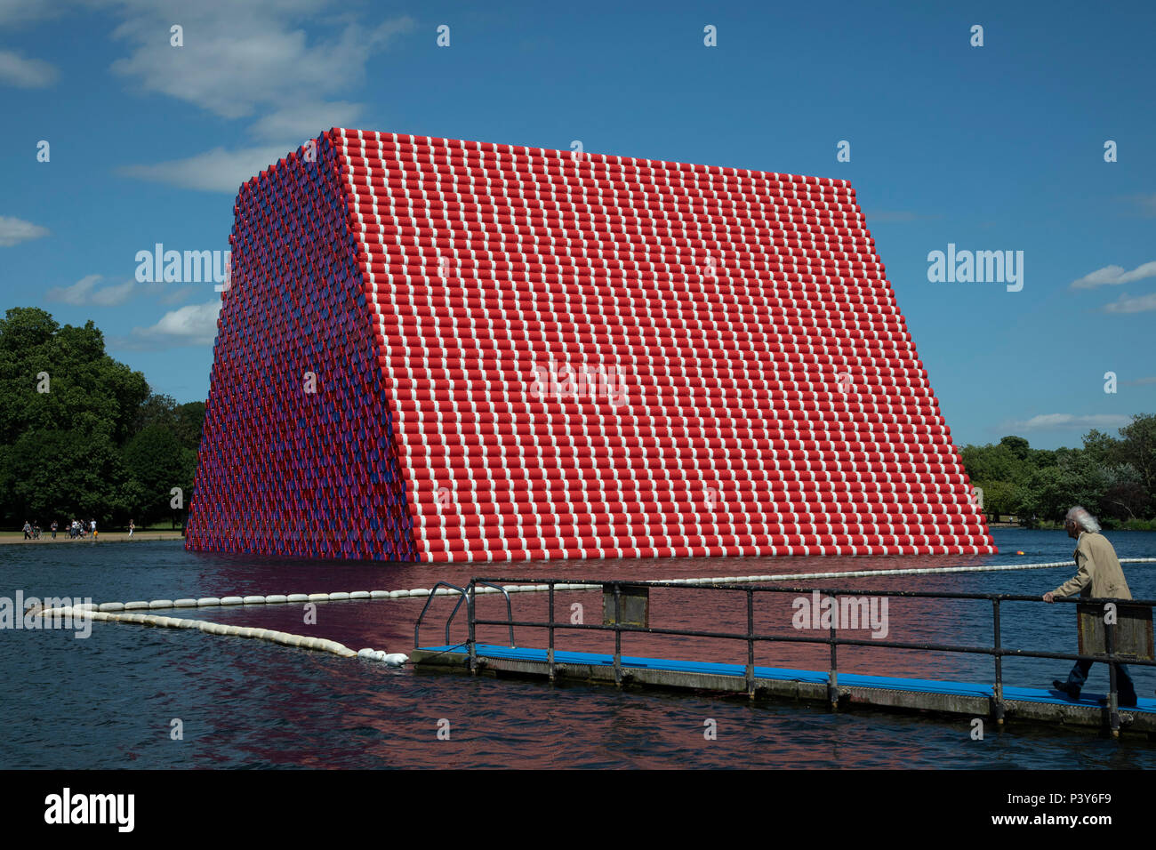 Artist Christo walks out onto a pontoon to view his art installation The Mastaba, by artist Christo, installed on the Serpentine lake in Hyde Park on June 18th 2018 in London, United Kingdom. The sculpture consists of 7,506 stacked barrels, painted in shades of red, white, blue and mauve. The completed piece forms part of an exhibition by Christo and his late wife, Jeanne-Claudes work, entitled Christo and Jeanne-Claude: Barrels and The Mastaba 19582018 to be held at The Serpentine Gallery. Stock Photo