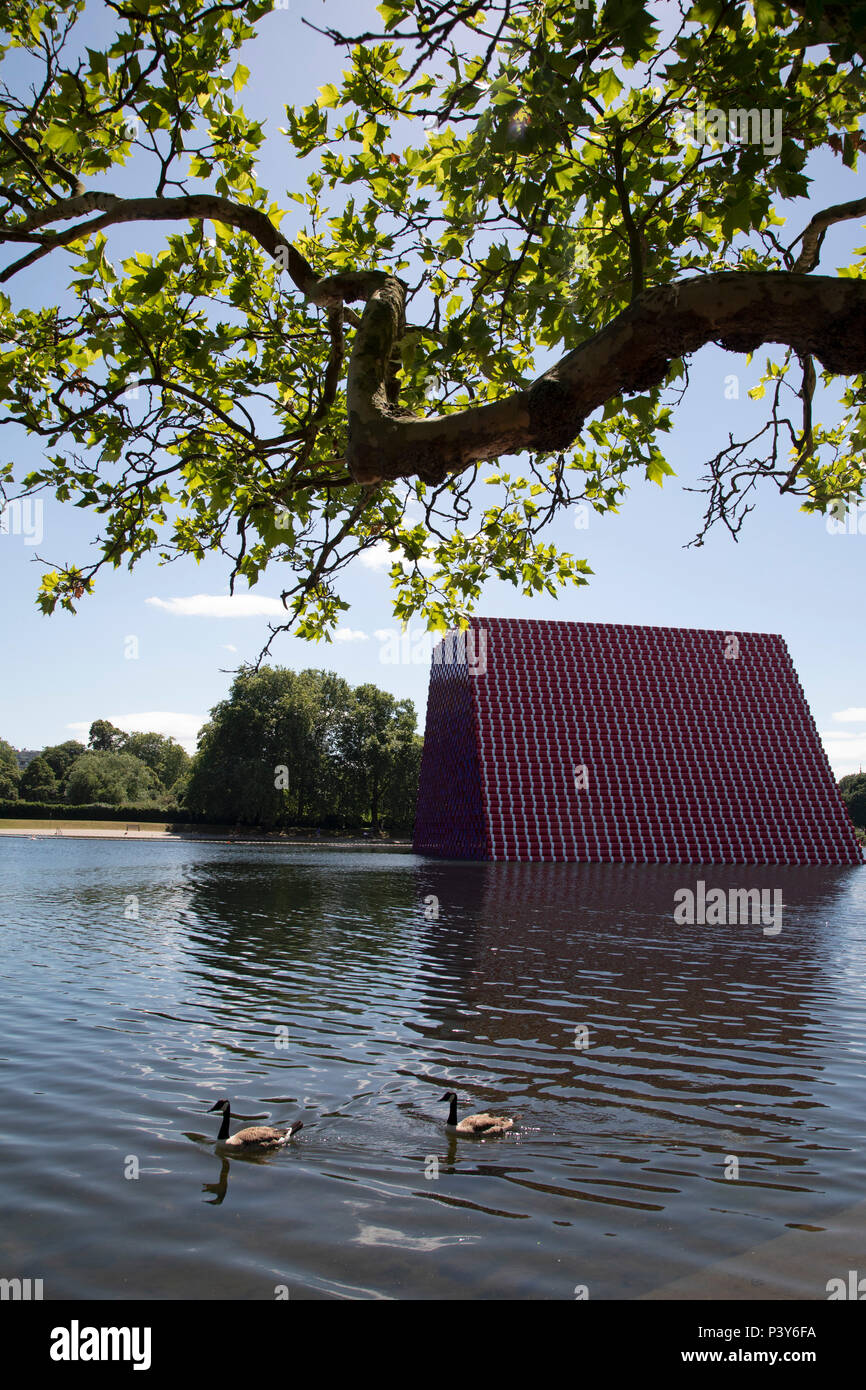 Art installation The Mastaba, by artist Christo, installed on the Serpentine lake in Hyde Park on June 18th 2018 in London, United Kingdom. The sculpture consists of 7,506 stacked barrels, painted in shades of red, white, blue and mauve. The completed piece forms part of an exhibition by Christo and his late wife, Jeanne-Claudes work, entitled Christo and Jeanne-Claude: Barrels and The Mastaba 19582018 to be held at The Serpentine Gallery. Stock Photo