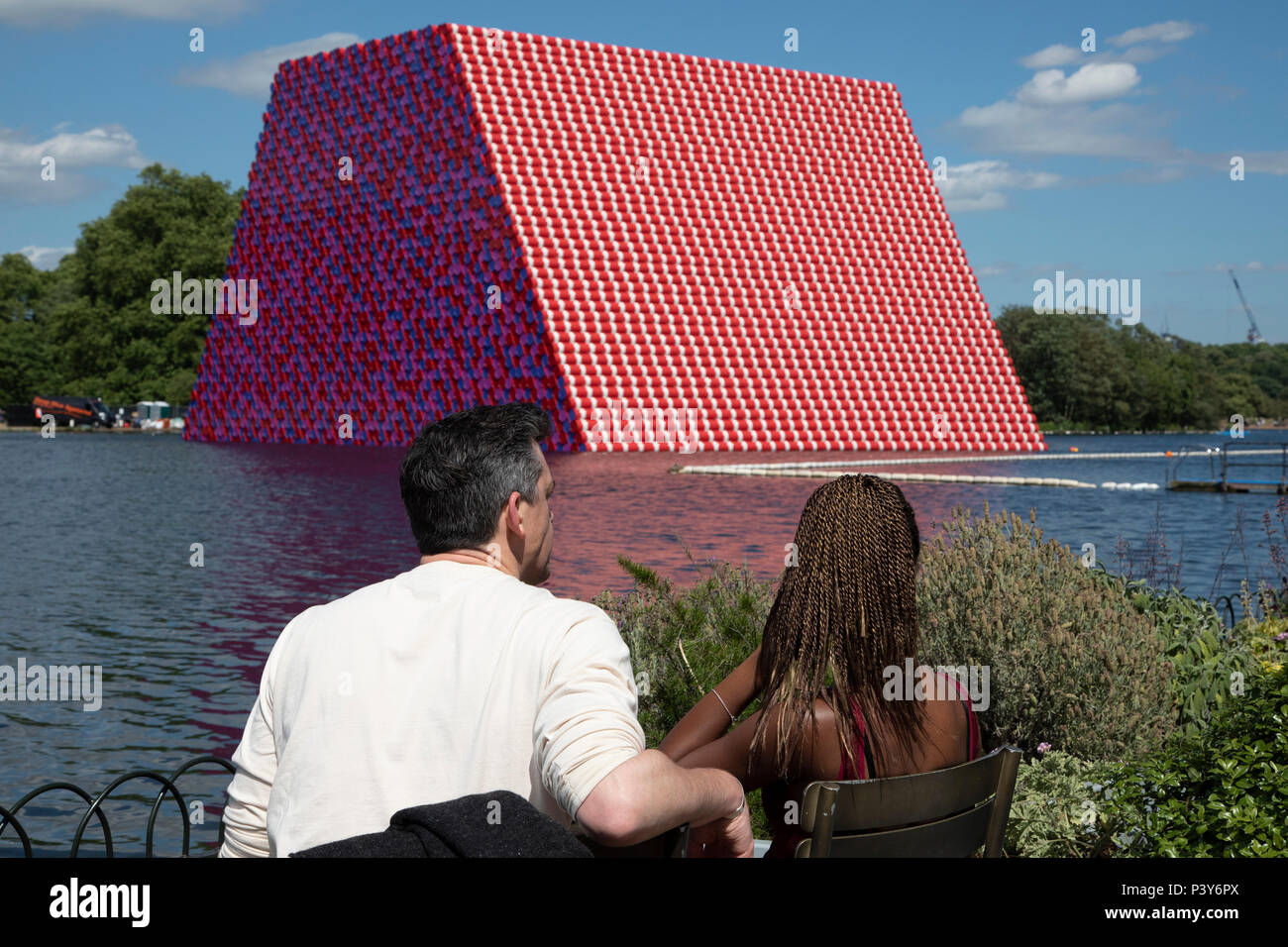Art installation The Mastaba, by artist Christo, installed on the Serpentine lake in Hyde Park on June 18th 2018 in London, United Kingdom. The sculpture consists of 7,506 stacked barrels, painted in shades of red, white, blue and mauve. The completed piece forms part of an exhibition by Christo and his late wife, Jeanne-Claudes work, entitled Christo and Jeanne-Claude: Barrels and The Mastaba 19582018 to be held at The Serpentine Gallery. Stock Photo