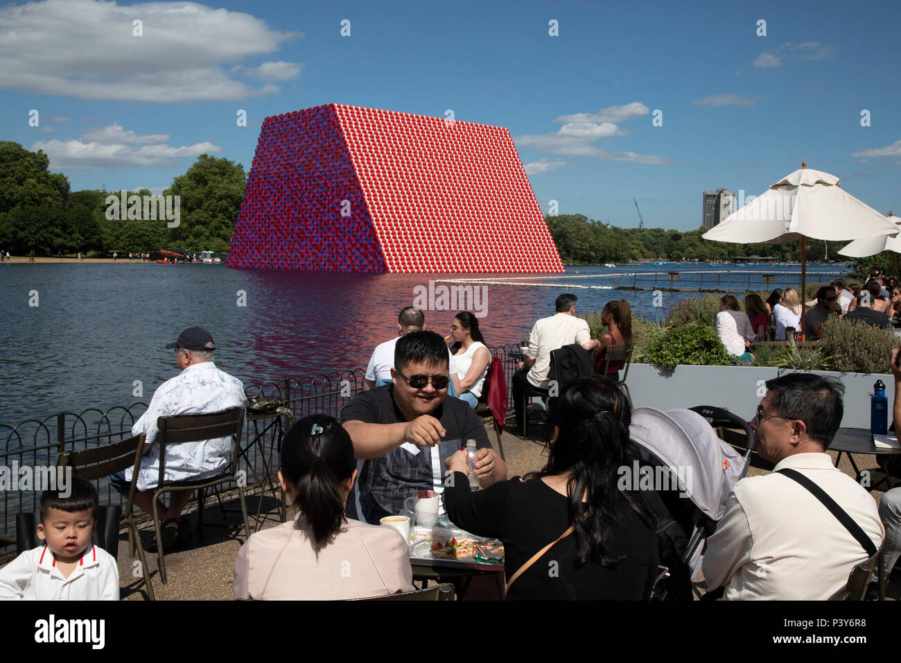 Art installation The Mastaba, by artist Christo, installed on the Serpentine lake in Hyde Park on June 18th 2018 in London, United Kingdom. The sculpture consists of 7,506 stacked barrels, painted in shades of red, white, blue and mauve. The completed piece forms part of an exhibition by Christo and his late wife, Jeanne-Claudes work, entitled Christo and Jeanne-Claude: Barrels and The Mastaba 19582018 to be held at The Serpentine Gallery. Stock Photo