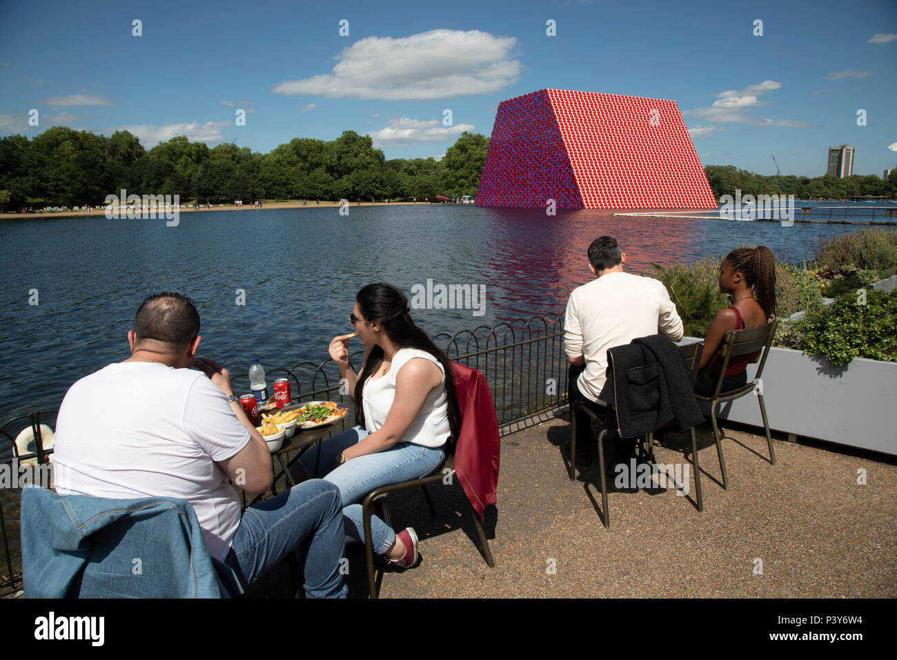Art installation The Mastaba, by artist Christo, installed on the Serpentine lake in Hyde Park on June 18th 2018 in London, United Kingdom. The sculpture consists of 7,506 stacked barrels, painted in shades of red, white, blue and mauve. The completed piece forms part of an exhibition by Christo and his late wife, Jeanne-Claudes work, entitled Christo and Jeanne-Claude: Barrels and The Mastaba 19582018 to be held at The Serpentine Gallery. Stock Photo