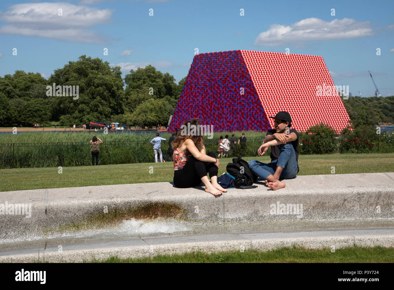 Art installation The Mastaba, by artist Christo, installed on the Serpentine lake in Hyde Park on June 18th 2018 in London, United Kingdom. The sculpture consists of 7,506 stacked barrels, painted in shades of red, white, blue and mauve. The completed piece forms part of an exhibition by Christo and his late wife, Jeanne-Claudes work, entitled Christo and Jeanne-Claude: Barrels and The Mastaba 19582018 to be held at The Serpentine Gallery. Stock Photo