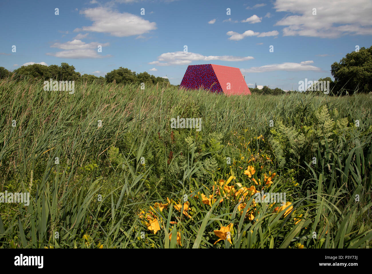 Art installation The Mastaba, by artist Christo, installed on the Serpentine lake in Hyde Park on June 18th 2018 in London, United Kingdom. The sculpture consists of 7,506 stacked barrels, painted in shades of red, white, blue and mauve. The completed piece forms part of an exhibition by Christo and his late wife, Jeanne-Claudes work, entitled Christo and Jeanne-Claude: Barrels and The Mastaba 19582018 to be held at The Serpentine Gallery. Stock Photo