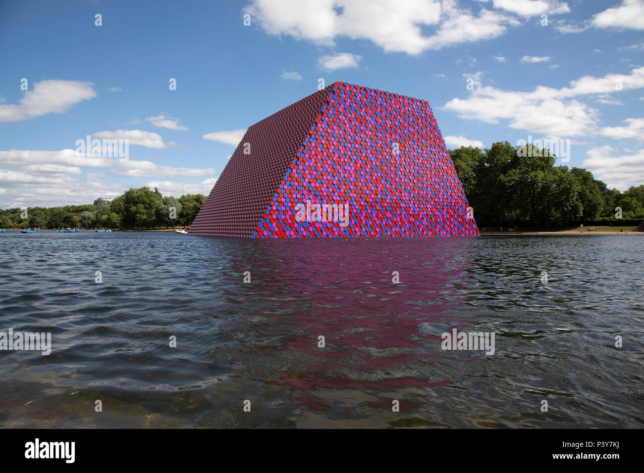 Art installation The Mastaba, by artist Christo, installed on the Serpentine lake in Hyde Park on June 18th 2018 in London, United Kingdom. The sculpture consists of 7,506 stacked barrels, painted in shades of red, white, blue and mauve. The completed piece forms part of an exhibition by Christo and his late wife, Jeanne-Claudes work, entitled Christo and Jeanne-Claude: Barrels and The Mastaba 19582018 to be held at The Serpentine Gallery. Stock Photo