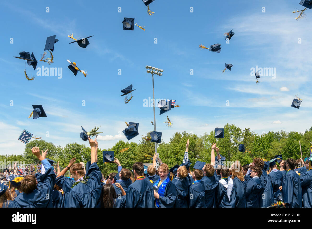 High school graduates throw their caps in the air at the end of a commencement ceremony. Stock Photo