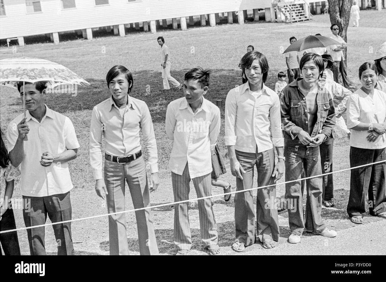FORT SMITH, AR, USA - AUGUST 10, 1975 -- Young Vietnamese men and other refugees stand along the road that President Gerald Ford's limo will pass as he arrives to tour the Fort Chaffee Vietnamese refugee center. Stock Photo