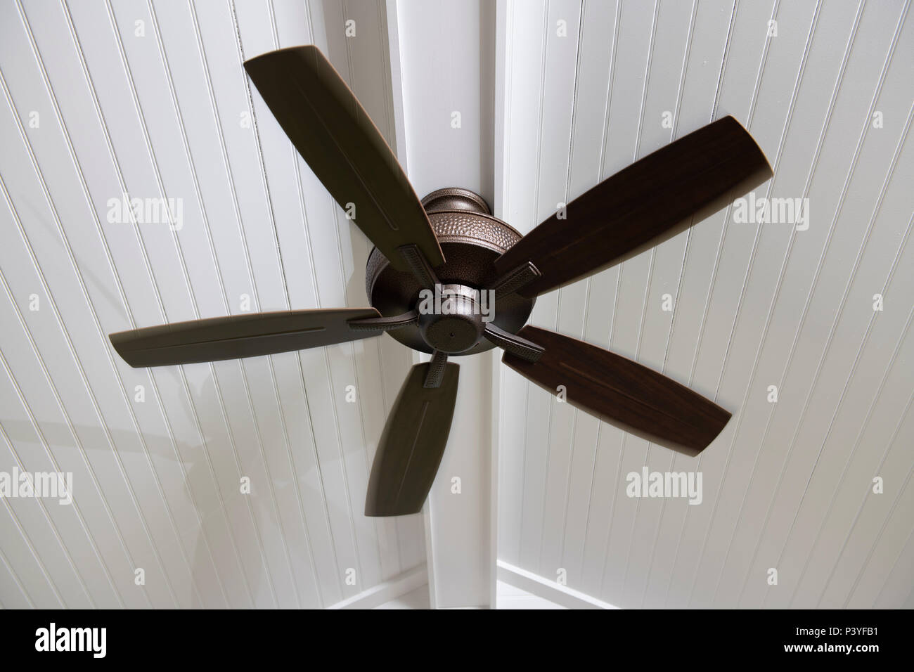 A modern electric ceiling fan on a screened in porch to help cool the space on a hot day Stock Photo