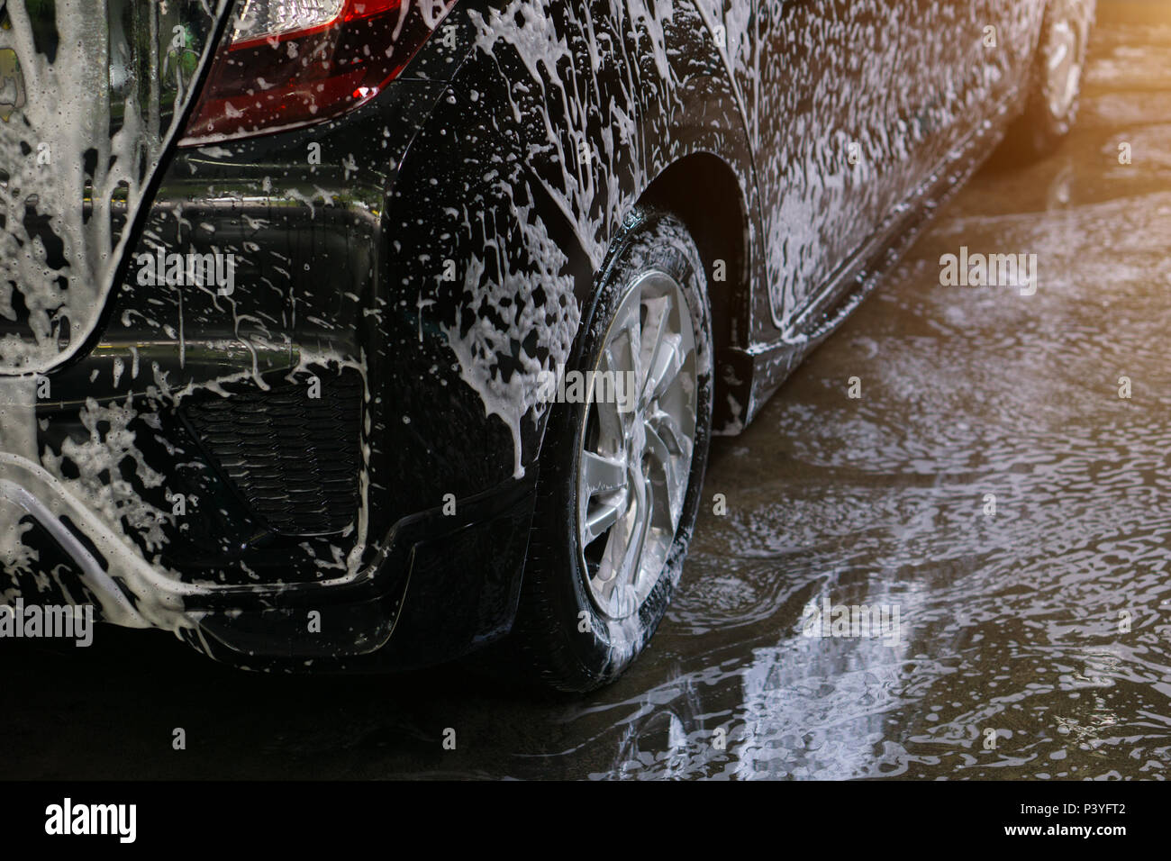 Selective focus of Black Car wash with soap and sunlight filter effect