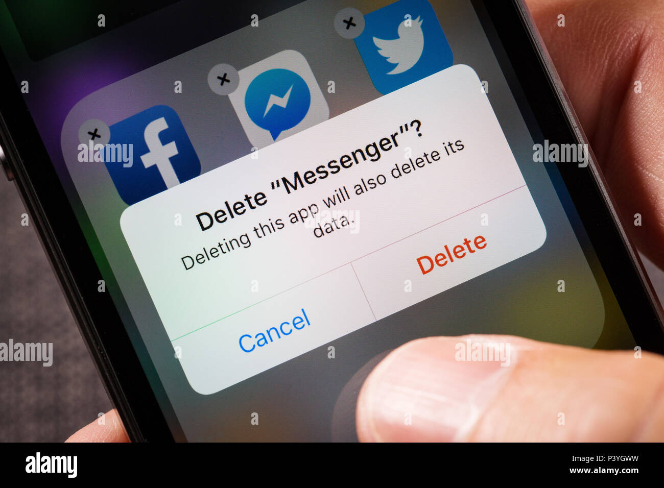 a man deleting Facebook Messenger from his phone Stock Photo