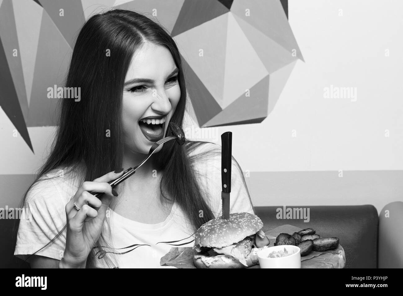 Laughing woman eating burger Stock Photo