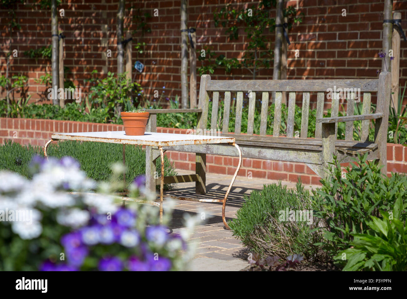 Garden patio seating area with view of brick retaining wall Stock Photo