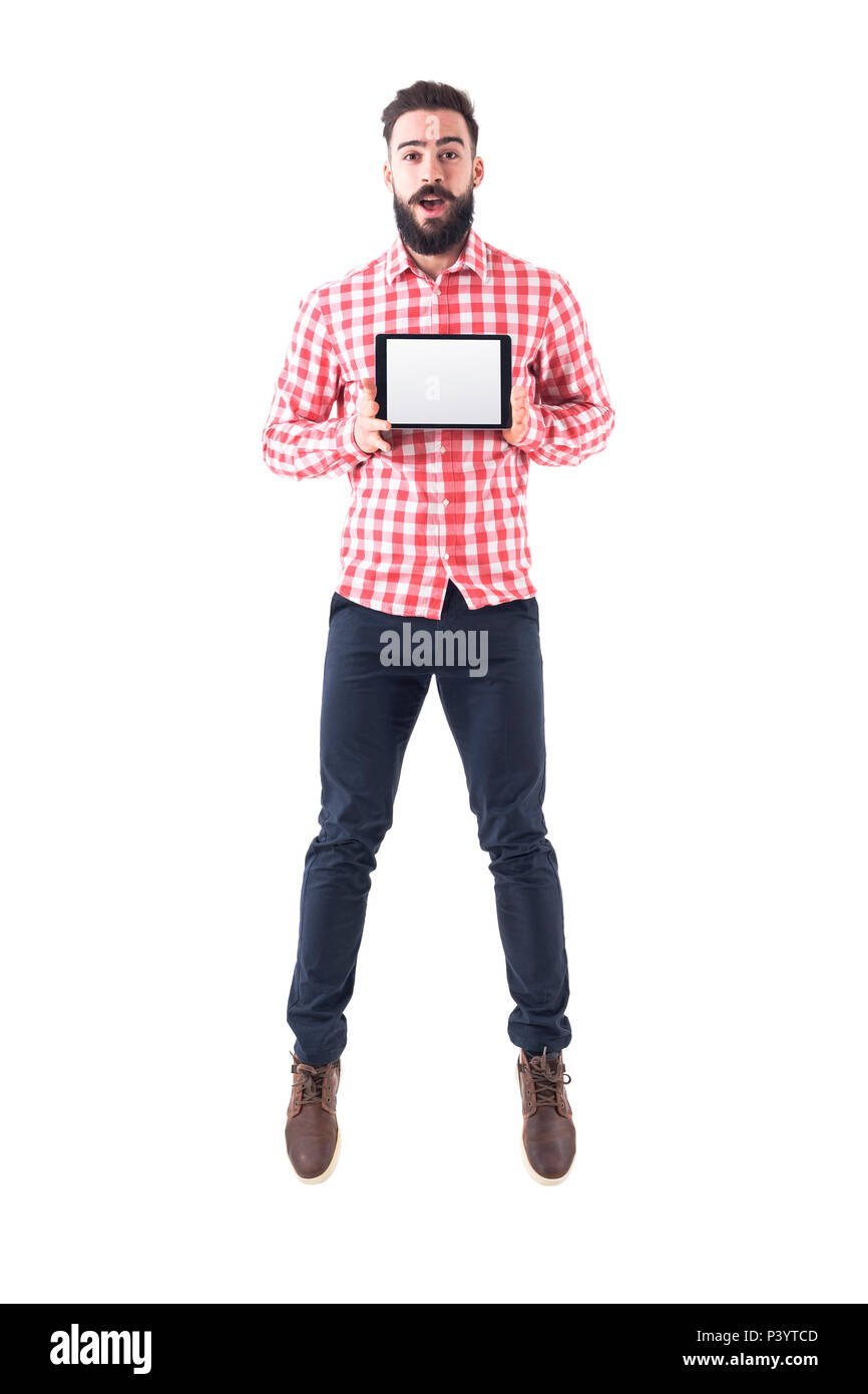 Ecstatic happy business man holding tablet with copyspace jumping in mid air and looking at camera. Full body isolated on white background. Stock Photo