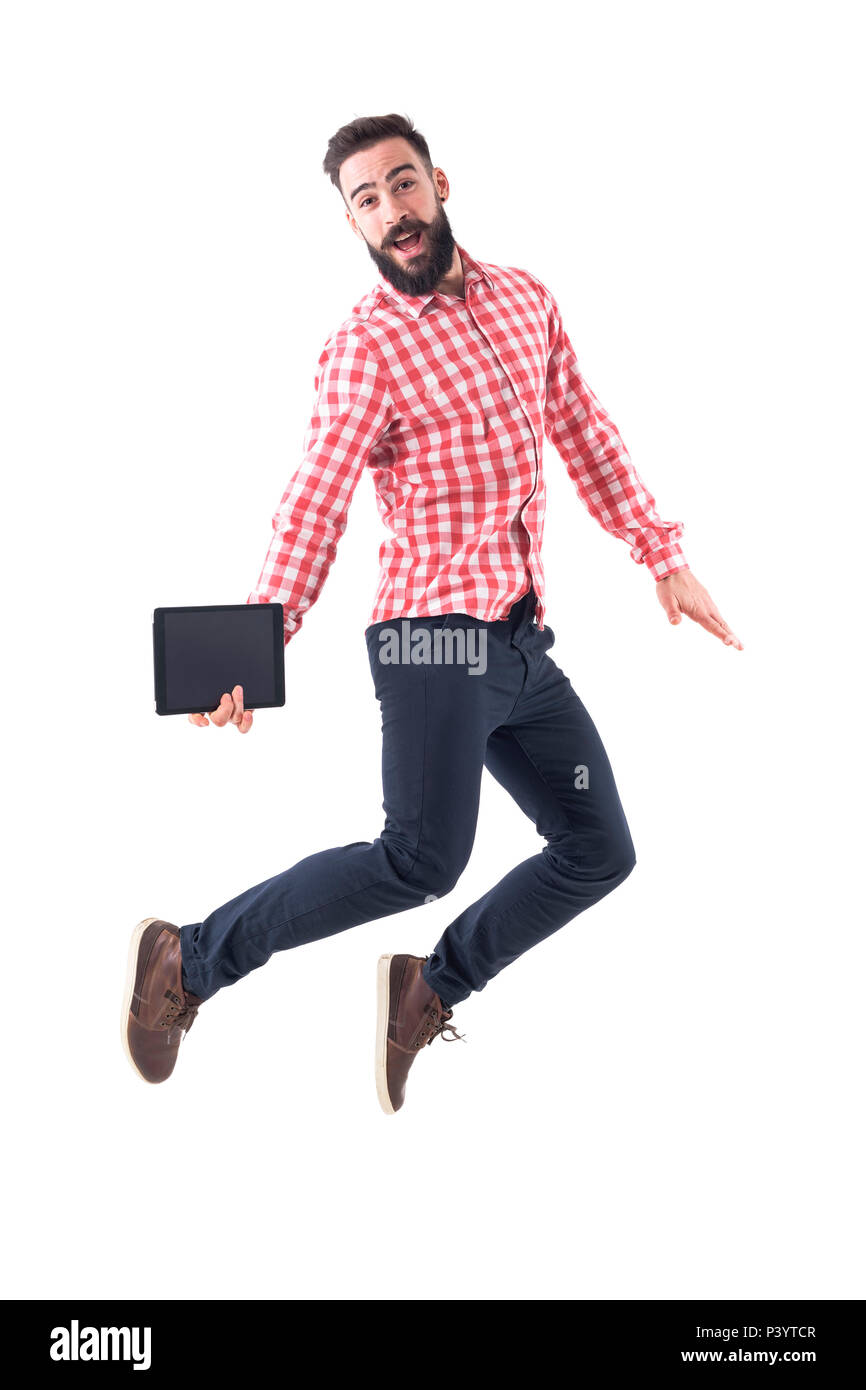 Successful excited young business man holding tablet jumping in mid air with open mouth. Full length isolated on white background. Stock Photo