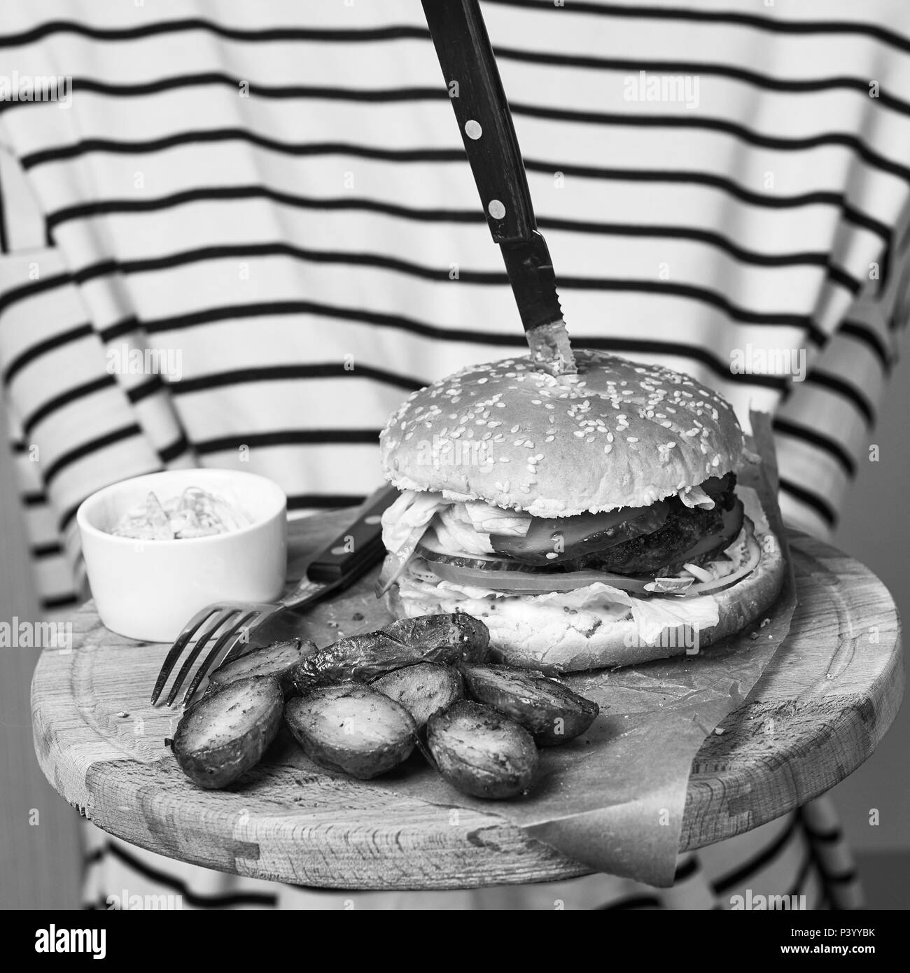 Woman serving steak on round wooden plate Stock Photo