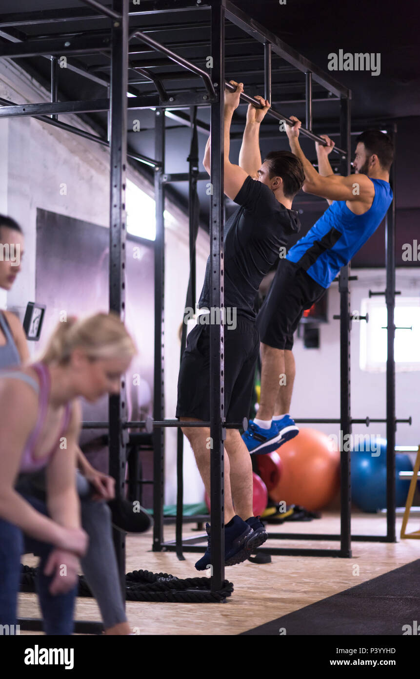 group of young muscular athletes doing pull ups on the horizontal bar ...
