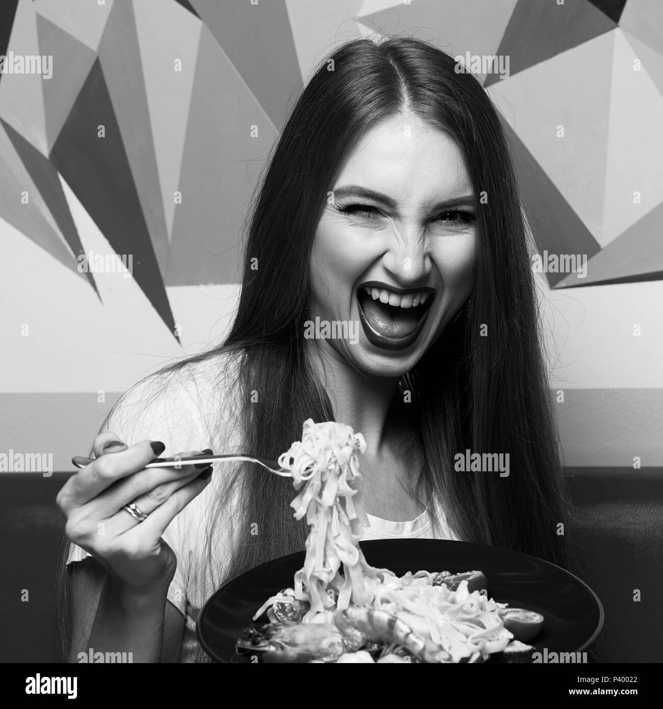 Beautiful woman with expressively opened mouth eating fettuccine Stock Photo