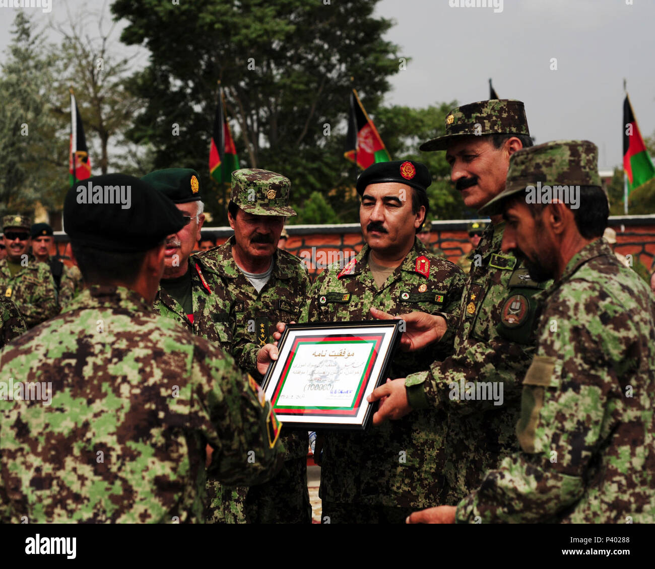 Afghan National Army Private Mohammed Khaili, the 100,000th BWC graduate to go through literacy training, is awarded a plaque and pen at Kabul Military Training Center in Kabul, Afghanistan, July 28, 2011, in recognition of the Afghan National Security Force's accomplishments in the realm of education and literacy. Basic Warrior Training Kandak 162 graduated 1,287 soldiers, all of whom will continue military and literacy training at various Afghan National Army Branch Schools or the Consolidated Fielding Cener in Kabul. Stock Photo