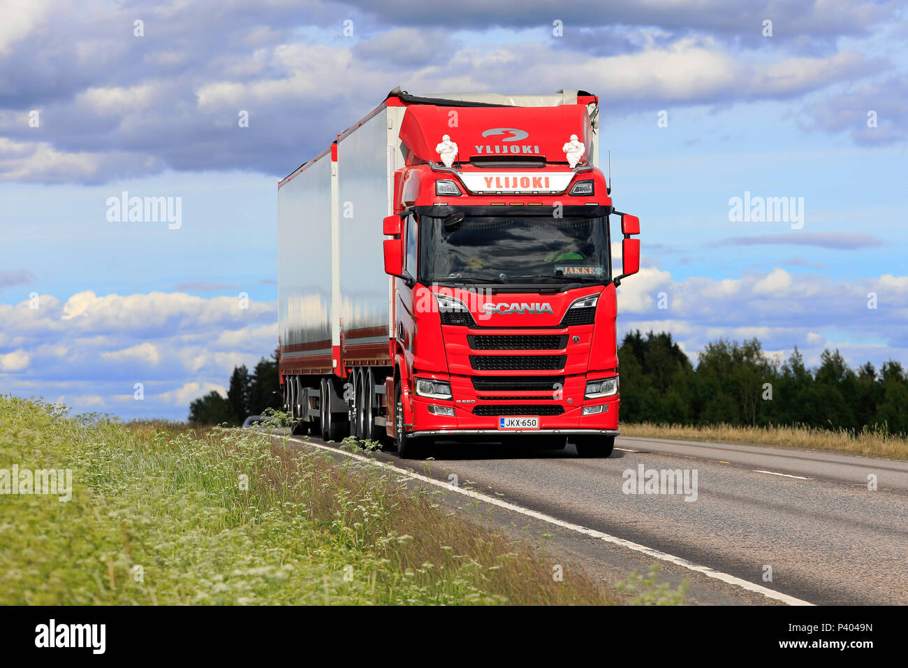 Red Next Generation Scania R650 truck and woodchip transport trailer of Ylijoki Kuljetus Oy up front in summer road landscape in Jamsa, Finland - June Stock Photo