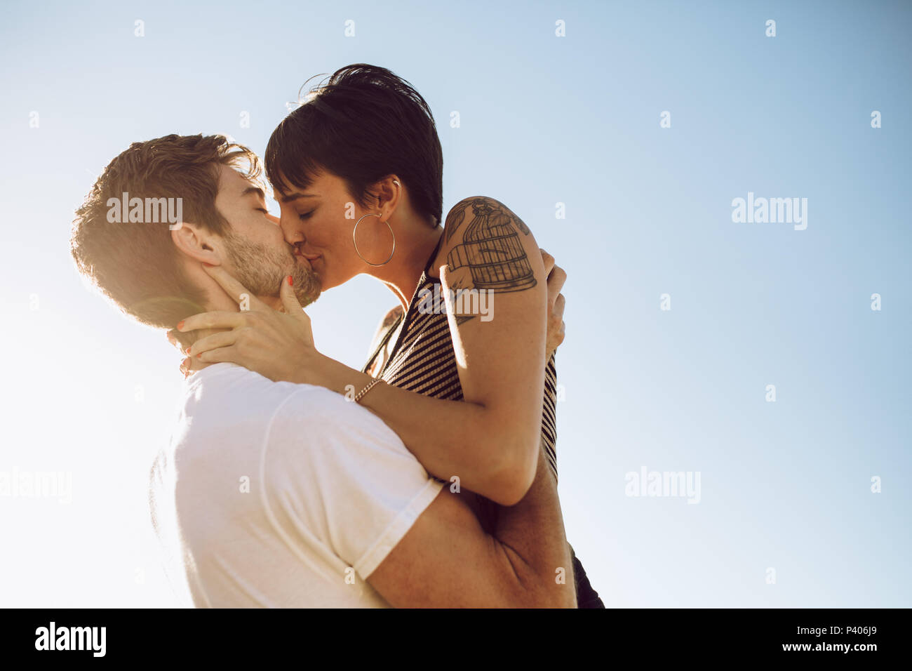 Beautiful couple kissing outdoors. Affectionate woman kissing her boyfriend. Stock Photo