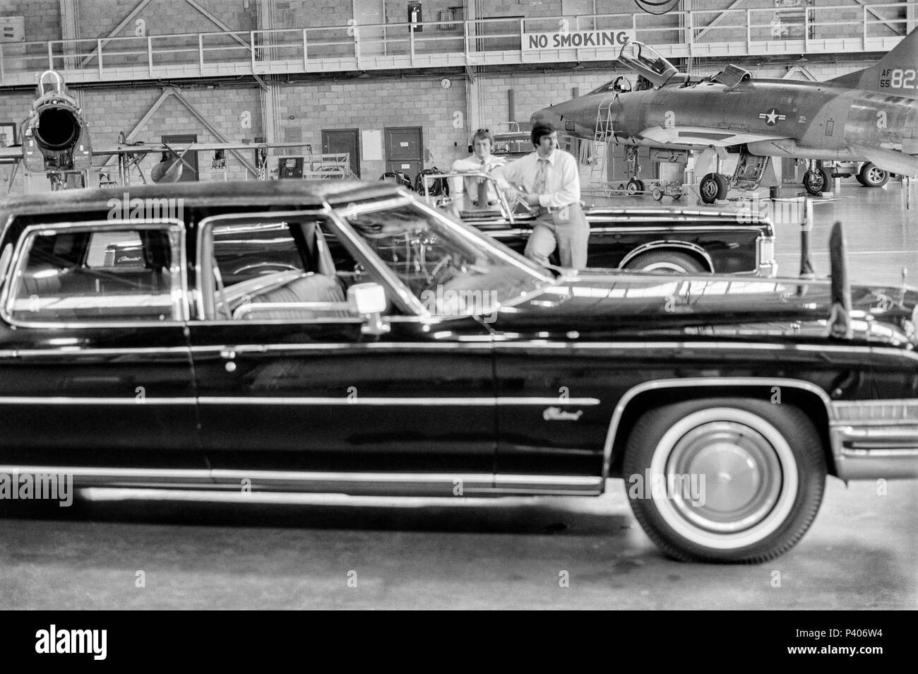 FORT SMITH, AR, USA - AUGUST 10, 1975 -- Two United States Secret Service agents keep watch  over the presidential limo in a secure military aircraft hanger while President Gerald Ford tours the new Vietnamese refugee center at Fort Chaffee, AR.  Focus is on the agents. Stock Photo